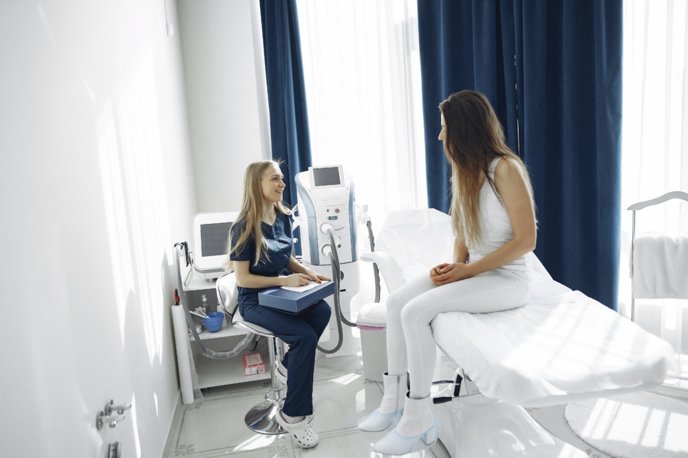 Patient sitting on a hospital bed while her nurse sits by a monitor. They are laughing and talking.